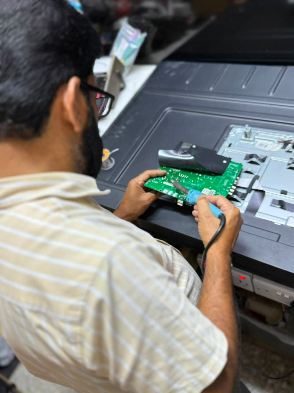 Technician soldering a TV mainboard